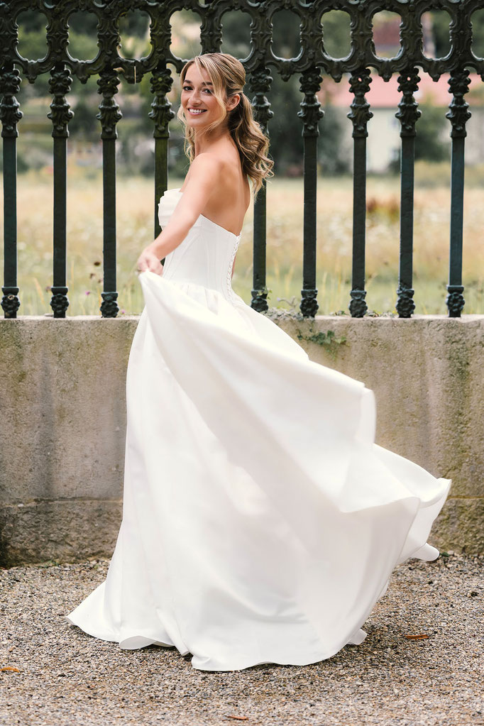 Blonde Frau trägt das Brautkleid Corinna aus der Amo&Luv Kollektion 2026