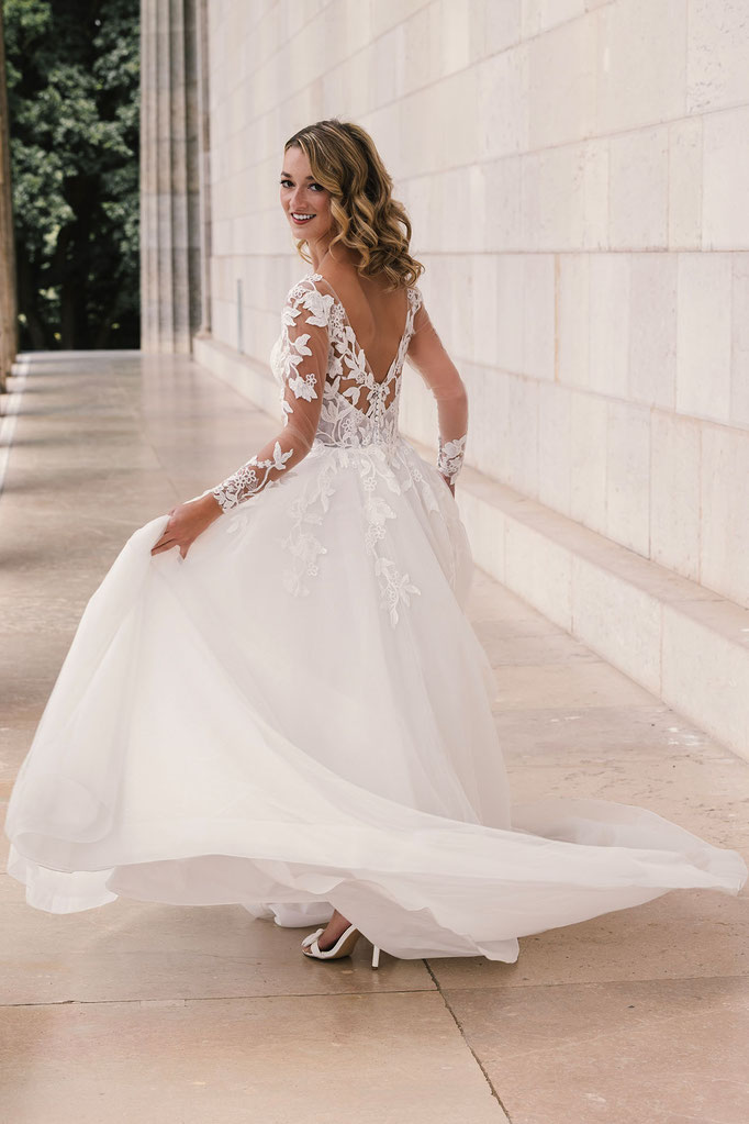 Blonde junge Frau in Bewegung trägt das Brautkleid Carla aus der Amo&Luv Kollektion 2026