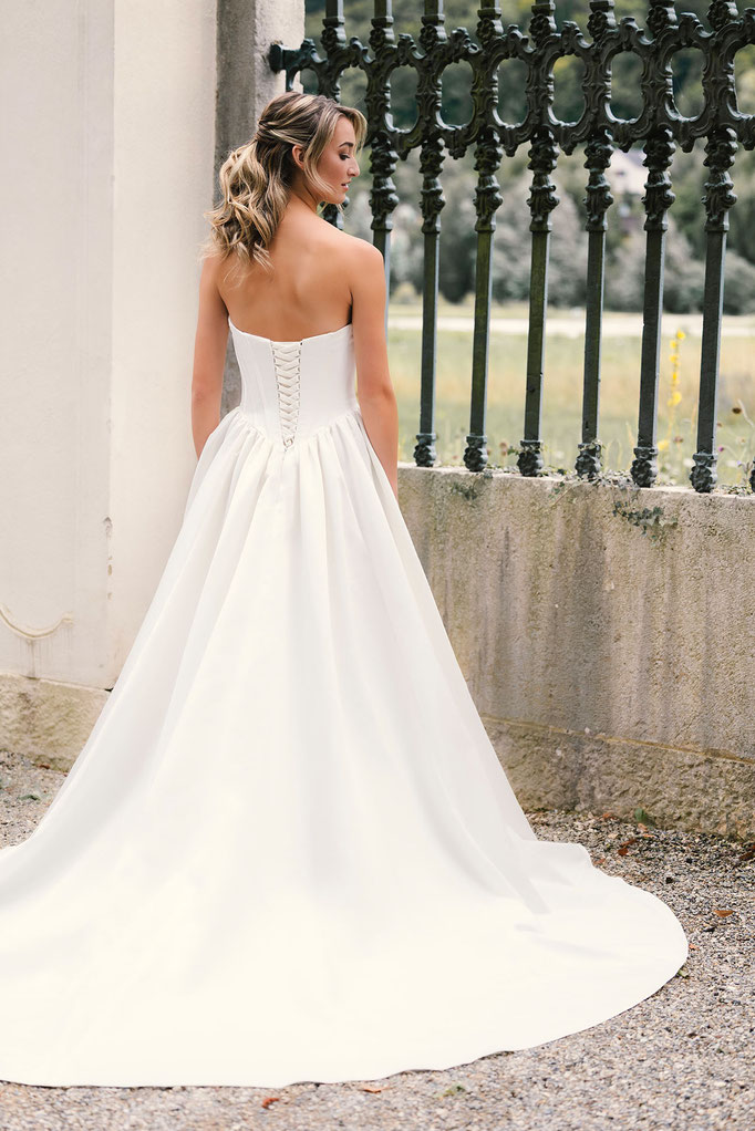 Blonde Frau trägt das Brautkleid Corinna aus der Amo&Luv Kollektion 2026