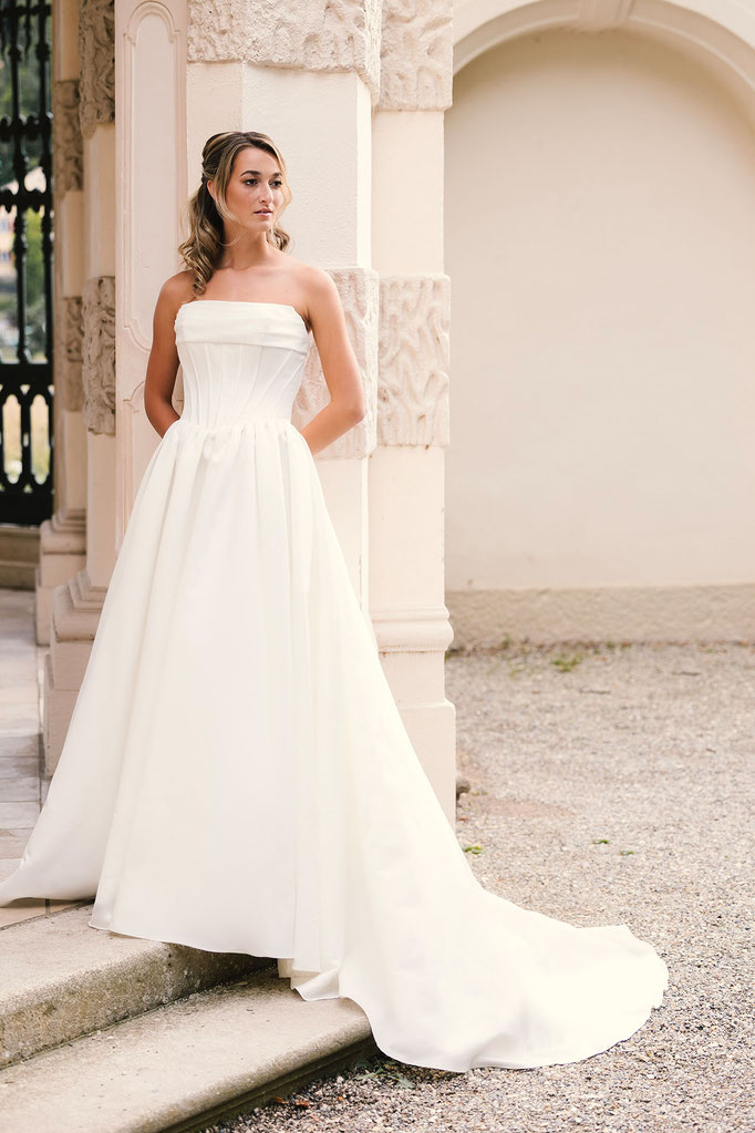 Blonde Frau trägt das Brautkleid Corinna aus der Amo&Luv Kollektion 2026