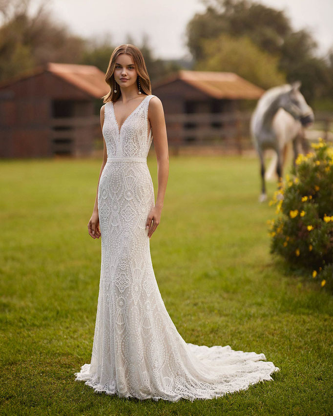 Junge Frau auf einer Pferdekoppel trägt das Brautkleid Numian aus der Alma Novia Kollektion 2026