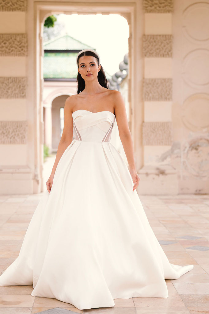 Frau mit braunen Haaren trägt ein Amo & Luv Brautkleid