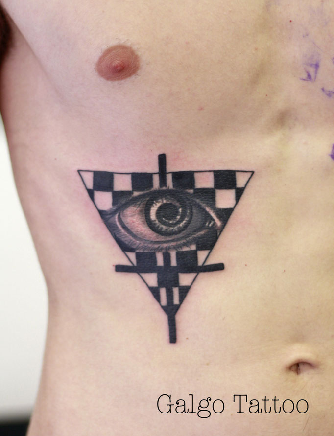 Tatuaje realista de un ojo illuminati dentro de un triángulo ajedrezado.