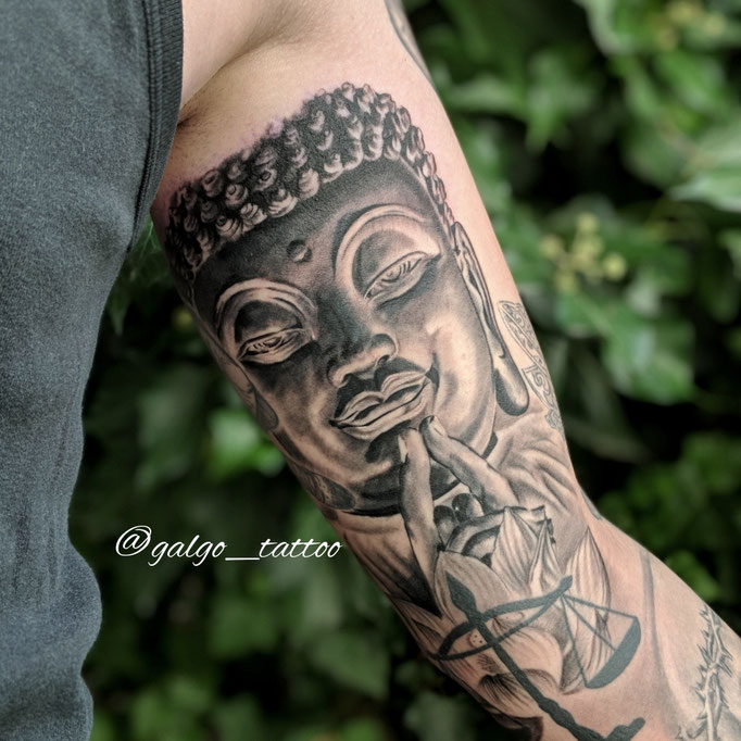 tatu realista de un Buda, hecho en black and grey en el interior del biceps.