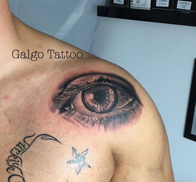 Un buen tatu de un ojo realista en blanco y negro, sobre el hombro.