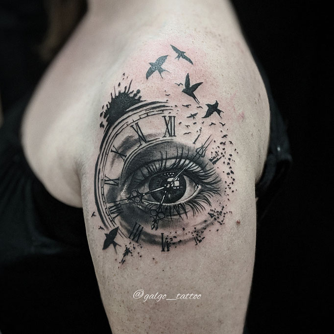 Tatuaje femenino realista con un ojo dentro de un reloj.