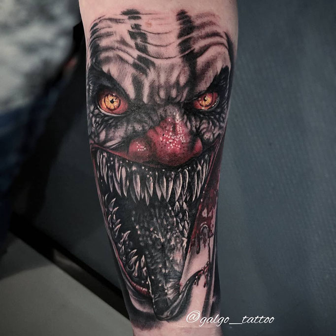 Tatuaje realista con un payaso diabólico, hecho en el antebrazo con color y grises.