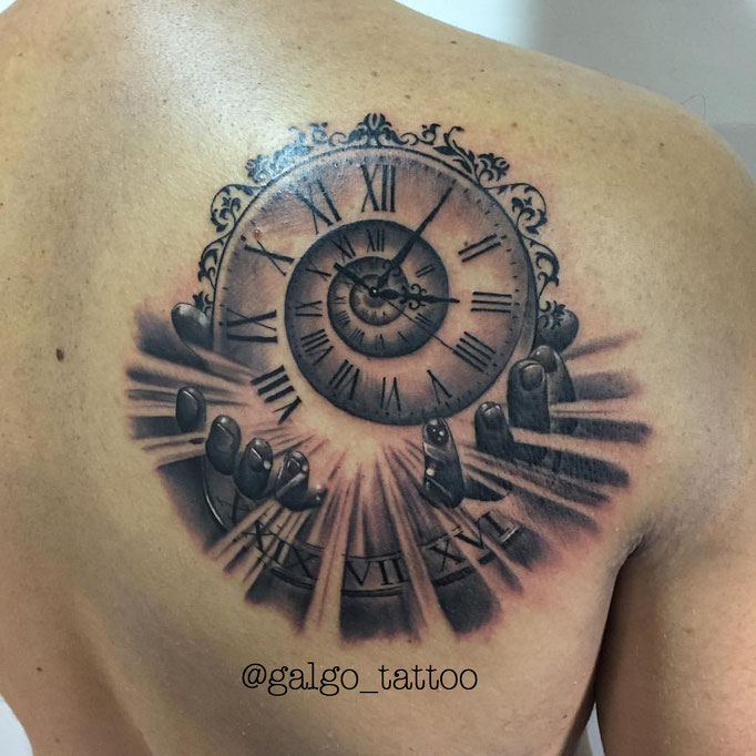 Tatuaje de un reloj con la hora de nacimiento, con unas manos que simbolizan la acogida en este mundo.