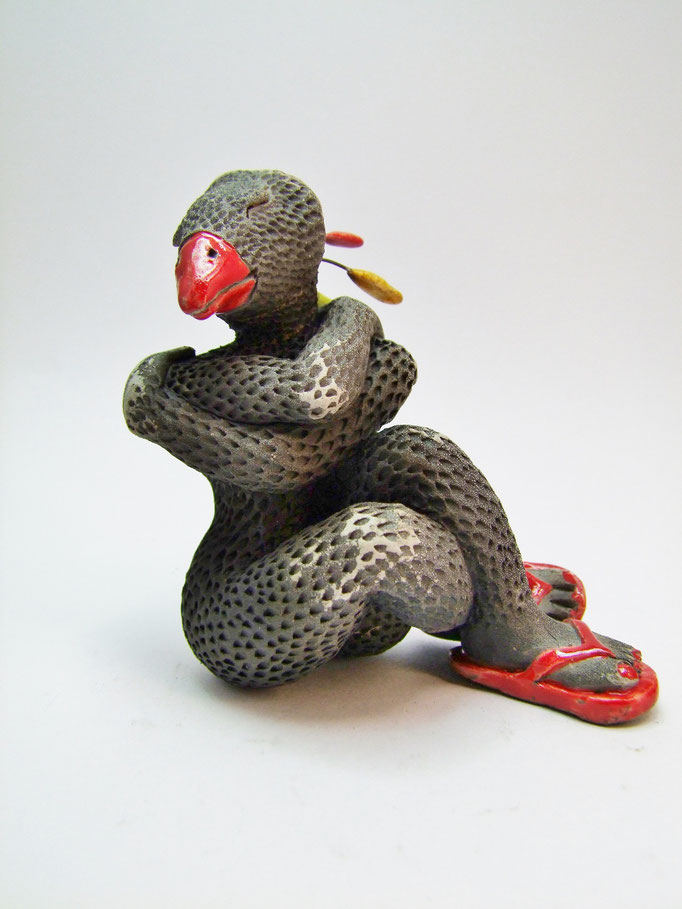 statue d'une femme à tête d'oiseau avec des tongues rouges