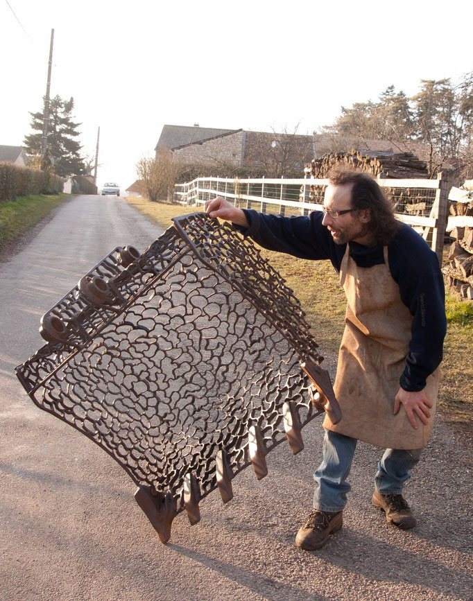 Sculpture en acier réalisée avec un godet de pelleteuse tenue par l'artiste