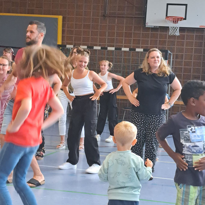 Schüler, Eltern und Lehrer tanzen gemeinsam den Macarena