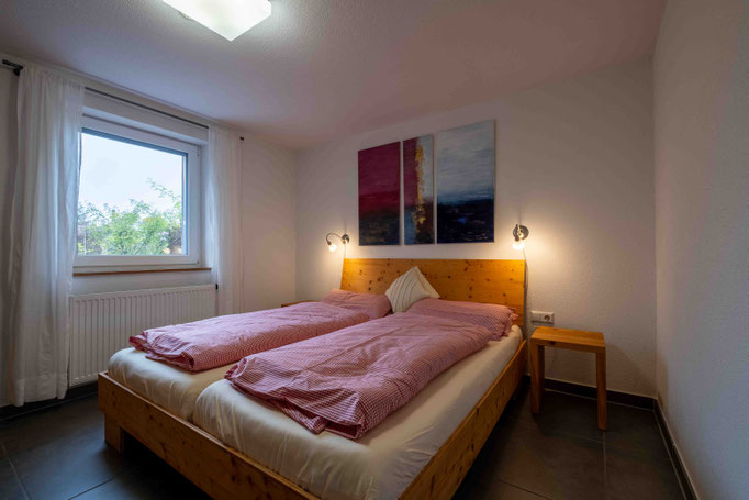 Doppelbett mit rotkarierter Bettwäsche und Nachttischlampen