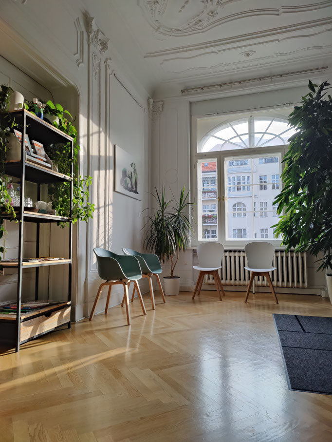Bright waiting room of Doumit Dental Practice in Berlin Friedenau featuring chairs, reception desk, and a large plant.