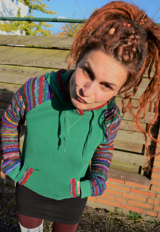 Kaputzenpulli mit Strickärmeln. Kaputze und Bauchtasche mit Wolle verziert.