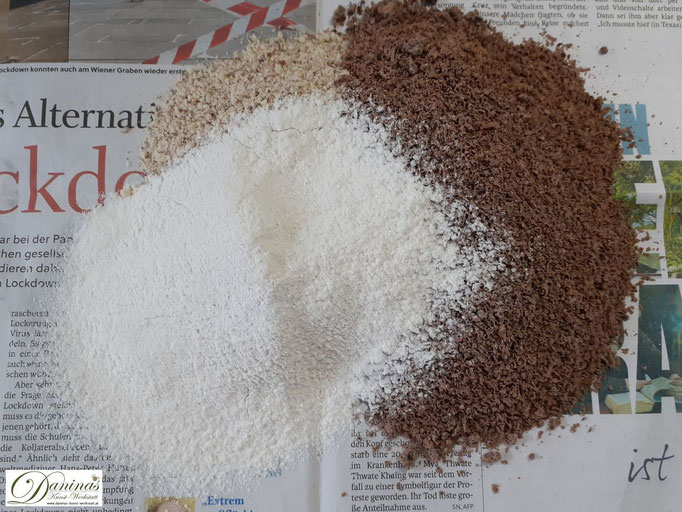 Mehl, Backpulver, geriebene Mandeln und Schokolade auf ein grroßes Zeitungspapier geben