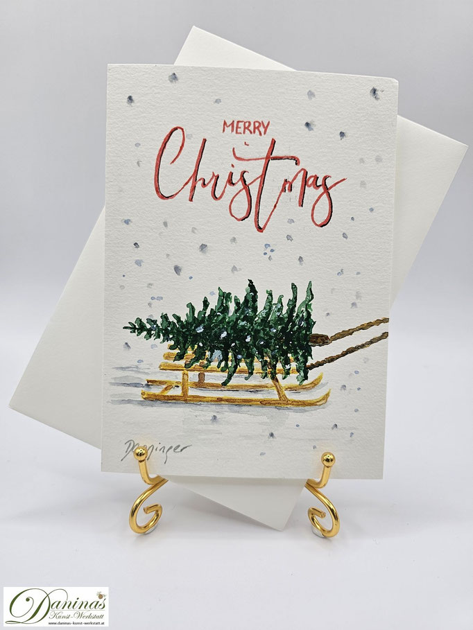 Weihnachtsgrußkarte gemalt Weihnachtsbaum auf Schlitten mit "Merry Christmas"-Handlettering
