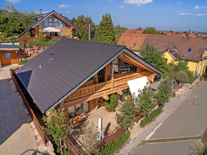 fotograf drohne - zwei blockhaus ferienhäuser im Sommer von seitlich 