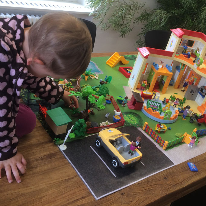 Mädchen spielt mit Playmobil auf der Spiel-Matte