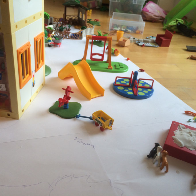 Spielmatte auf dem Boden mit einem Playmobil Spielplatz belegt
