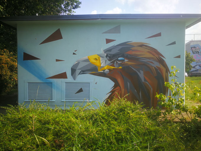 Großflächige geometrische Wandgestaltung auf einem Stromkasten, die einen Adlerkopf im Low-Poly-Stil zeigt. Moderne Fassadenkunst von Appolloart, umgesetzt deutschlandweit zur Stadtverschönerung.