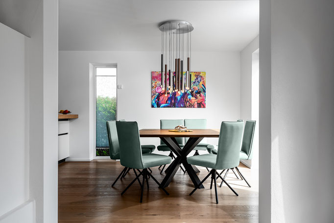 Interieuraufnahme Esszimmer: Tischgruppe mit grünen Stühlen und Kunstwerk, wohnlich modern