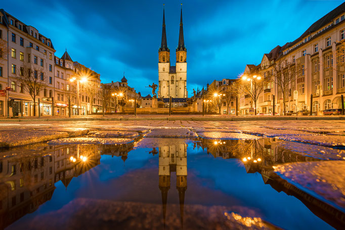 Blaue Türme und Hallmarkt spiegeln sich auf einer Pfütze