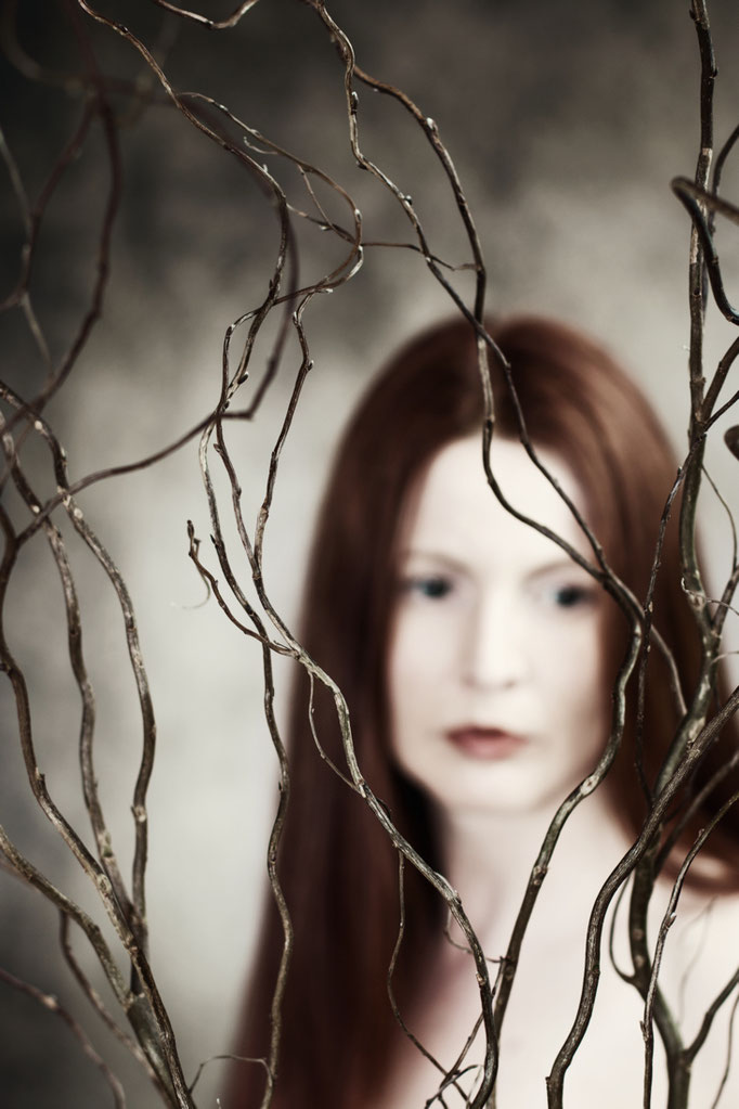 Manuela Deigert Bildsprache Poetisches Selbstportrait mit braunen Zweigen im Vordergrund