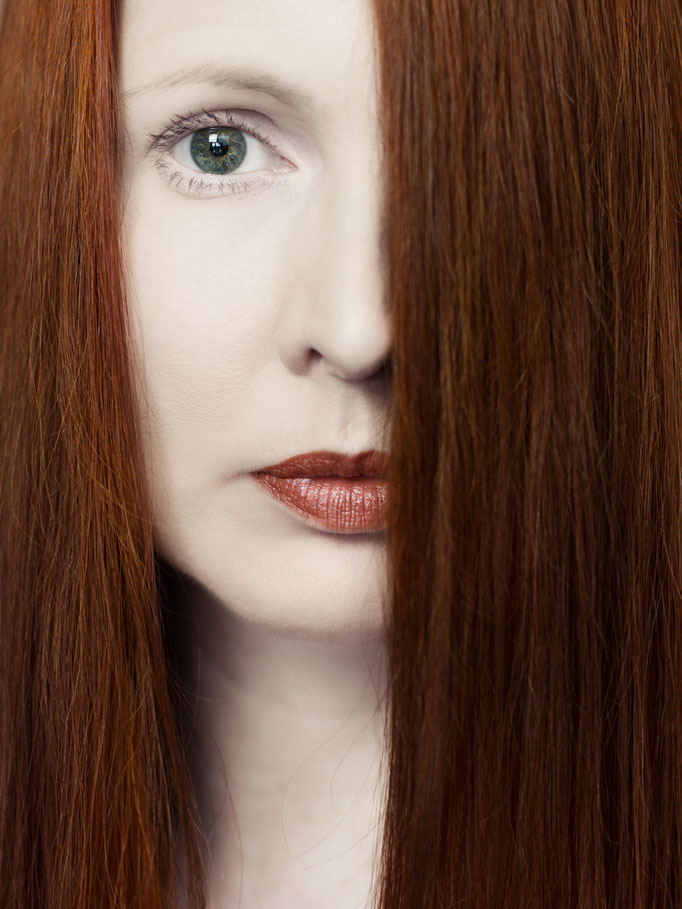 Manuela Deigert Bildsprache Selbstportrait mit roten Haaren vor einer Hälfte des Gesichtes