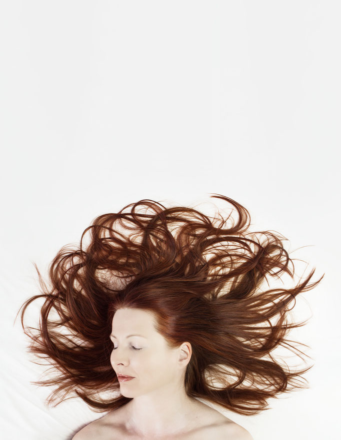 Manuela Deigert Bildsprache Selbstportrait liegend auf einem weissen Laken mit ausgebreitenden roten Haaren wie Tentakel