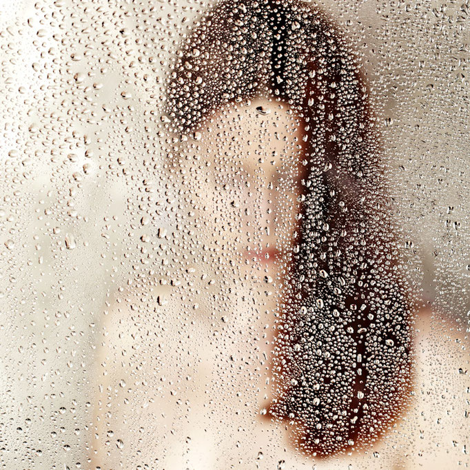 Manuela Deigert Bildsprache, melancholisches Selbstportrait hinter einer Scheibe mit Wassertropfen