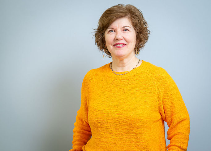 Businessportrait einer Frau in gelbem Pulli vor weissem Hintergrund.