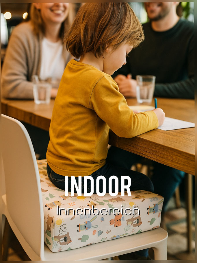 Kind sitzt im Restaurant mit einer Sitzerhöhung optimal am Tisch und malt