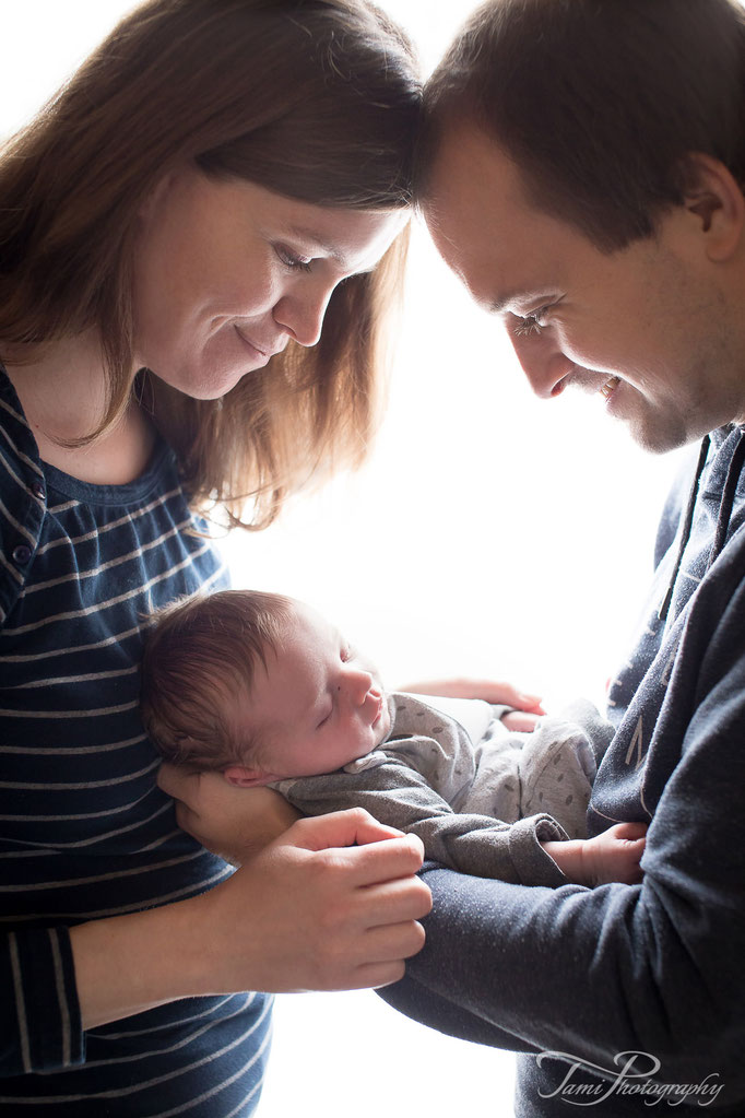 Babyfotograf Ulm – neue Eltern betrachten liebevoll ihr Neugeborenes zuhause