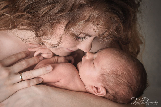 Natürliche Babyfotografie Ulm – Mutter hält ihr Baby liebevoll zuhause
