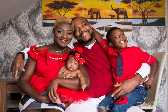 Familienfotografie Ulm – Familie in roten Oberteilen mit kleinem Jungen und Baby zuhause