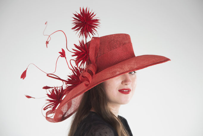 Red sinamay hat decorated with hand-made goose feather pompoms.