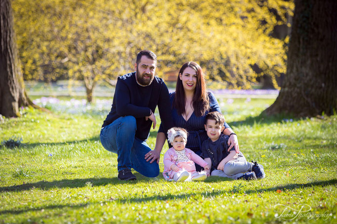 Familie sitzt beim Familienshooting im Gras im Park Alten Friedhof Ulm