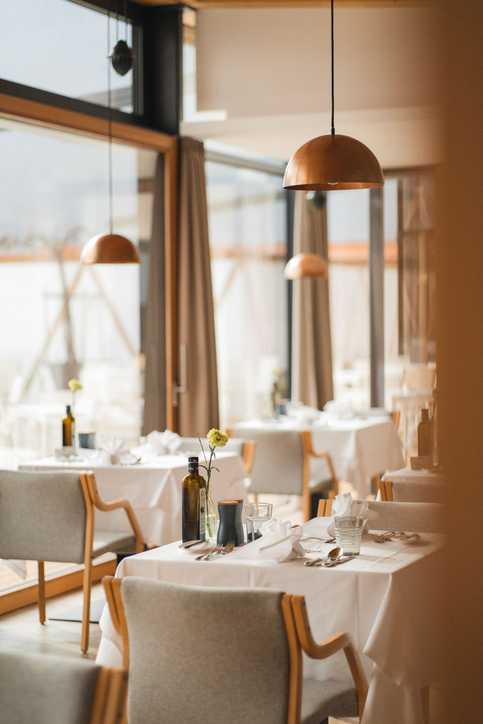 Helles Restaurant mit elegant gedeckten Tischen und warmen Pendelleuchten.