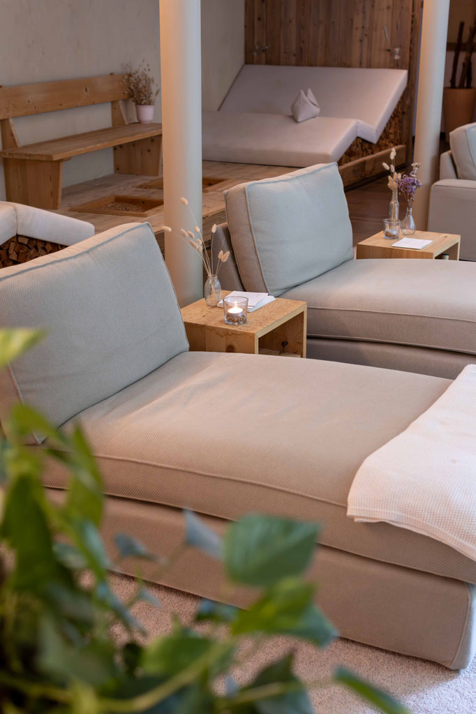 Heller Ruheraum mit komfortablen Relaxliegen, Kerzen und natürlichen Holzelementen im Wellnessbereich des Boutiquehotel PETRUS in Reischach-Bruneck • Südtirol, ideal zum Abschalten und Erholen.