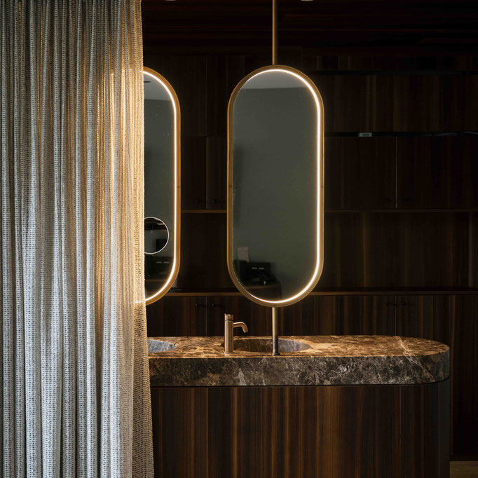 offenes Badezimmer mit Marmorplatte und ovalen Spiegeln in der Suite im Wellnesshotel Nesslerhof in Grossarl