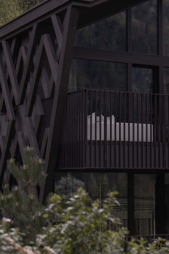 The modern façade of the Apfelhotel, featuring a striking wooden structure, large glass panels and a private balcony, set in natural surroundings.