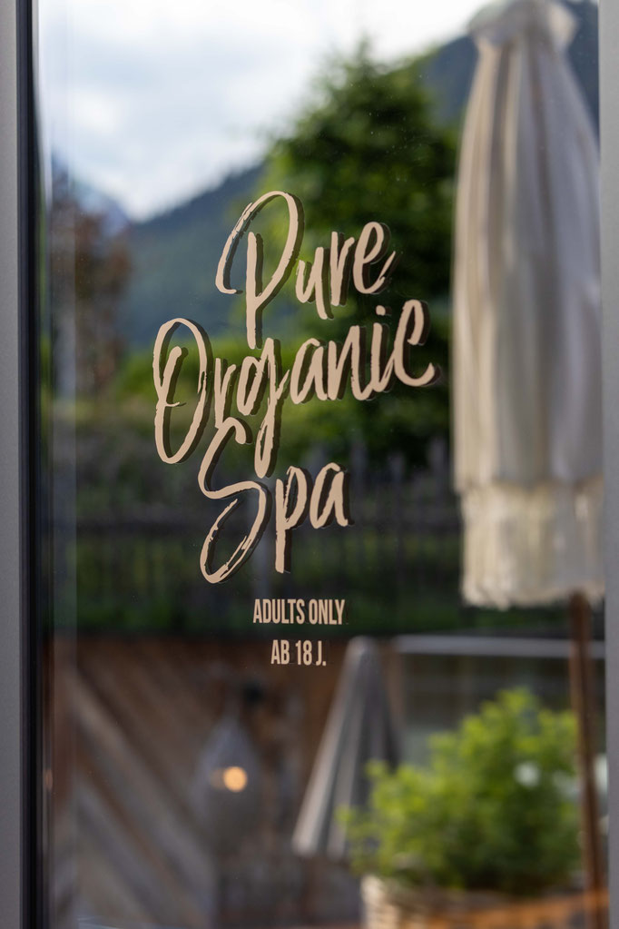 Eingang zum Pure Organic Spa im DER ENGEL im Tannheimertal mit der Aufschrift „Adults Only ab 18 J.“ auf einer Glastür. Im Hintergrund sorgen Naturmaterialien und die Bergkulisse für eine ruhige, exklusive Wellnessatmosphäre.