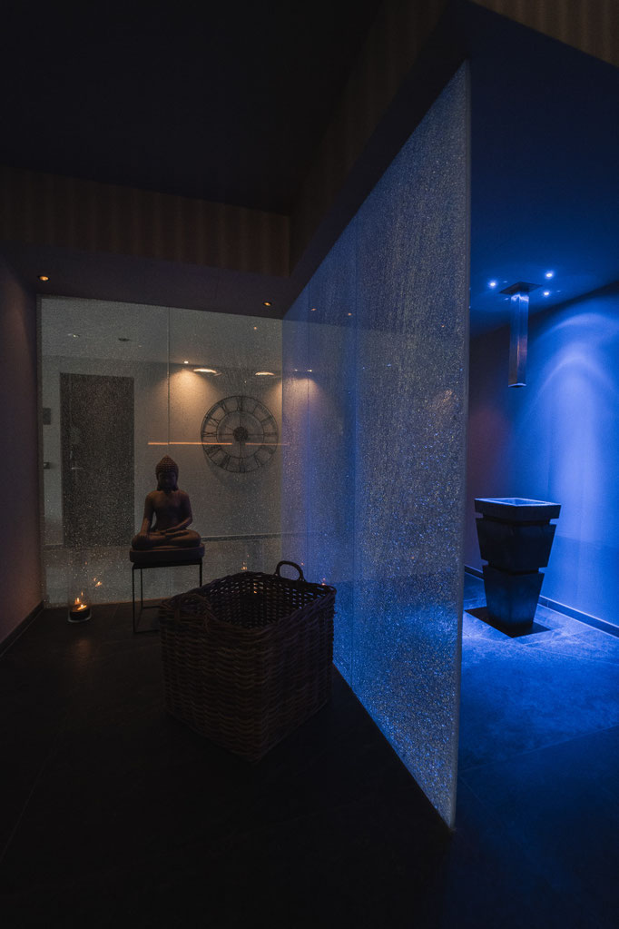 Modern gestalteter Wellnessbereich im Hotel Mair am Ort Living in Partschins bei Meran in Südtirol mit stimmungsvoll beleuchtetem Duschbereich, dekorativer Buddhafigur und ruhiger Atmosphäre für Entspannung und Erholung.