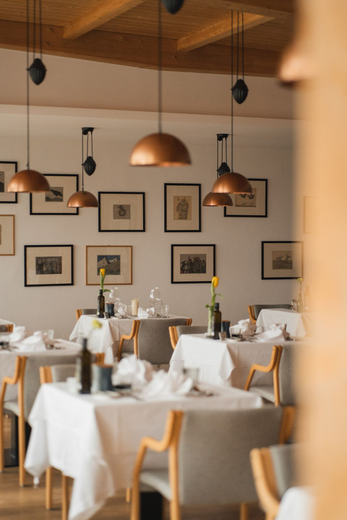 A modern restaurant with elegantly laid tables and copper-coloured pendant lights.