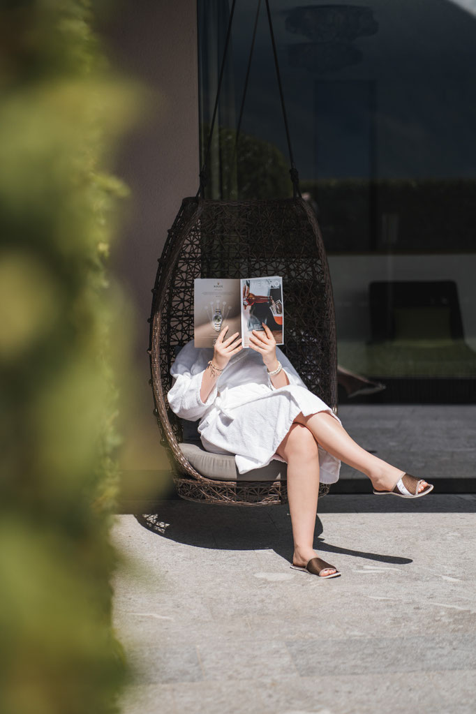 Woman reading in a hanging chair at the wellness area of VINEA Suites & Apartments