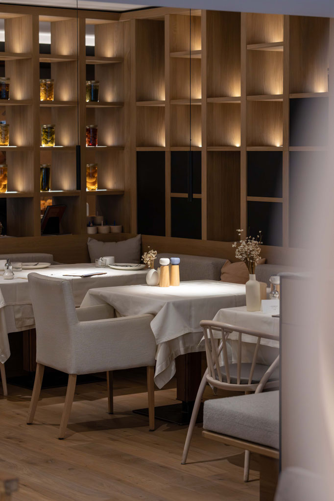 A stylishly furnished restaurant area with tables lovingly laid and warm wooden features at the PETRUS boutique hotel in Reischach-Bruneck • South Tyrol, inviting guests to relax and enjoy themselves.
