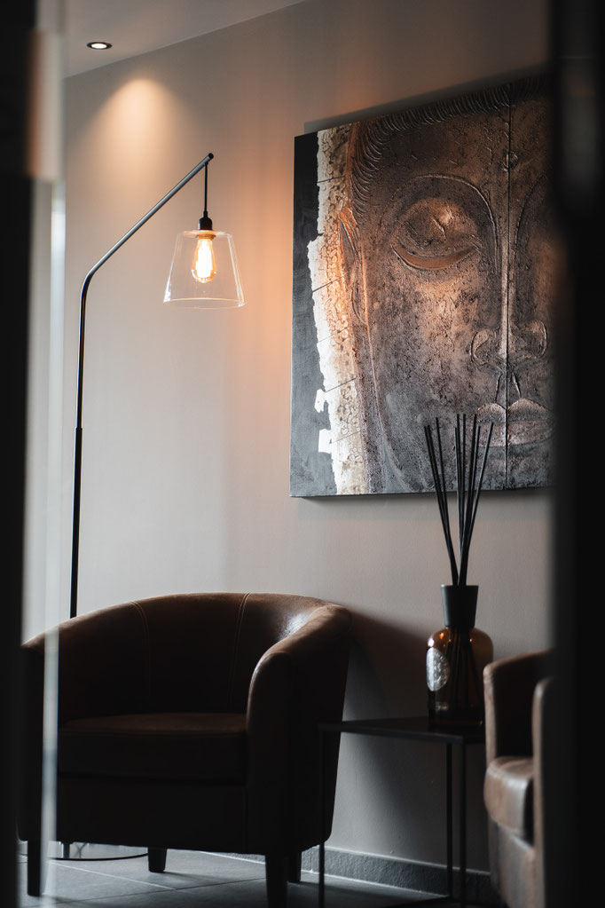 A stylishly designed relaxation area at the Hotel Mair am Ort Living in Partschins near Merano in South Tyrol, featuring a cosy leather armchair, a designer lamp and a decorative wall hanging. The harmonious décor creates a relaxed and inviting atmosphere