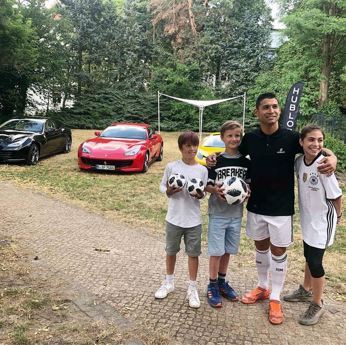 Fußball-Kindergeburtstag an einer besonderen Location mit Luxus-Autos im Hintergrund.