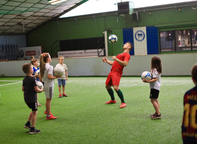 Fußball-Workshop in Berlin: Saki trainiert Kinder zum Geburtstag in einer Indoor-Halle.