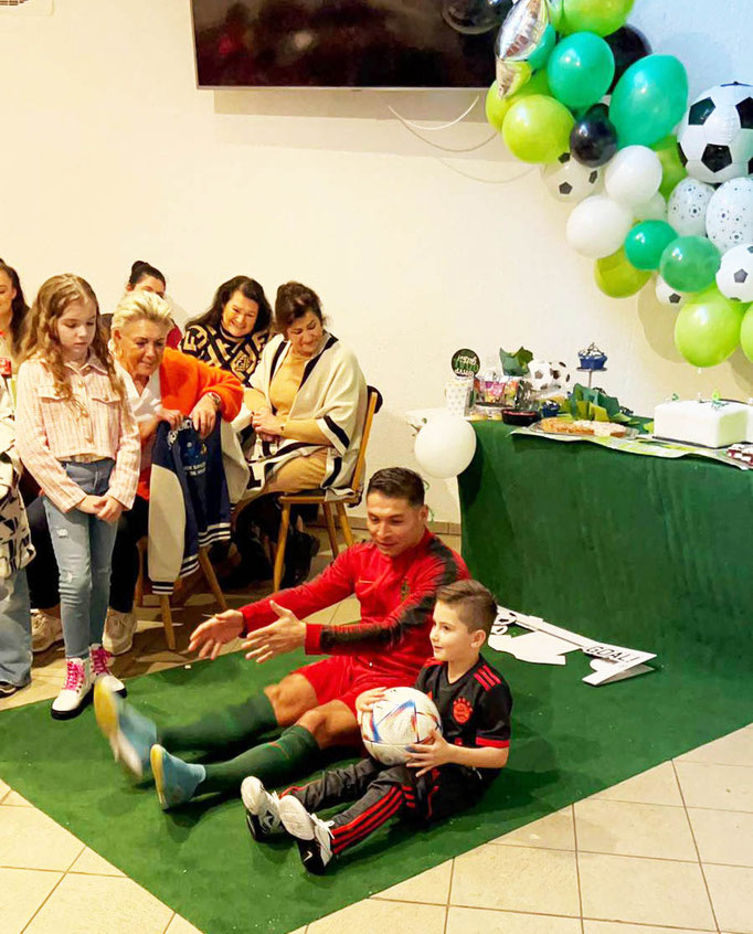 Fußballtraining für Kinder: Saki trainiert mit Spielern, während Eltern und Großeltern zuschauen.
